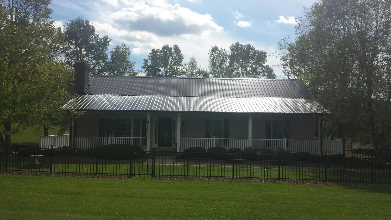 Gray metal roof on a brick ranch with a full width front porch — Gutter Guard Installation work by our crew in North Springfield