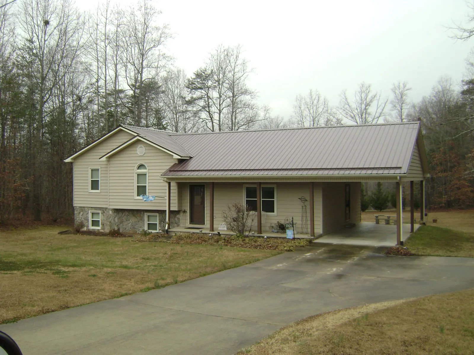 Brown metal roof on a tan split level home with an attached carport in North Springfield
